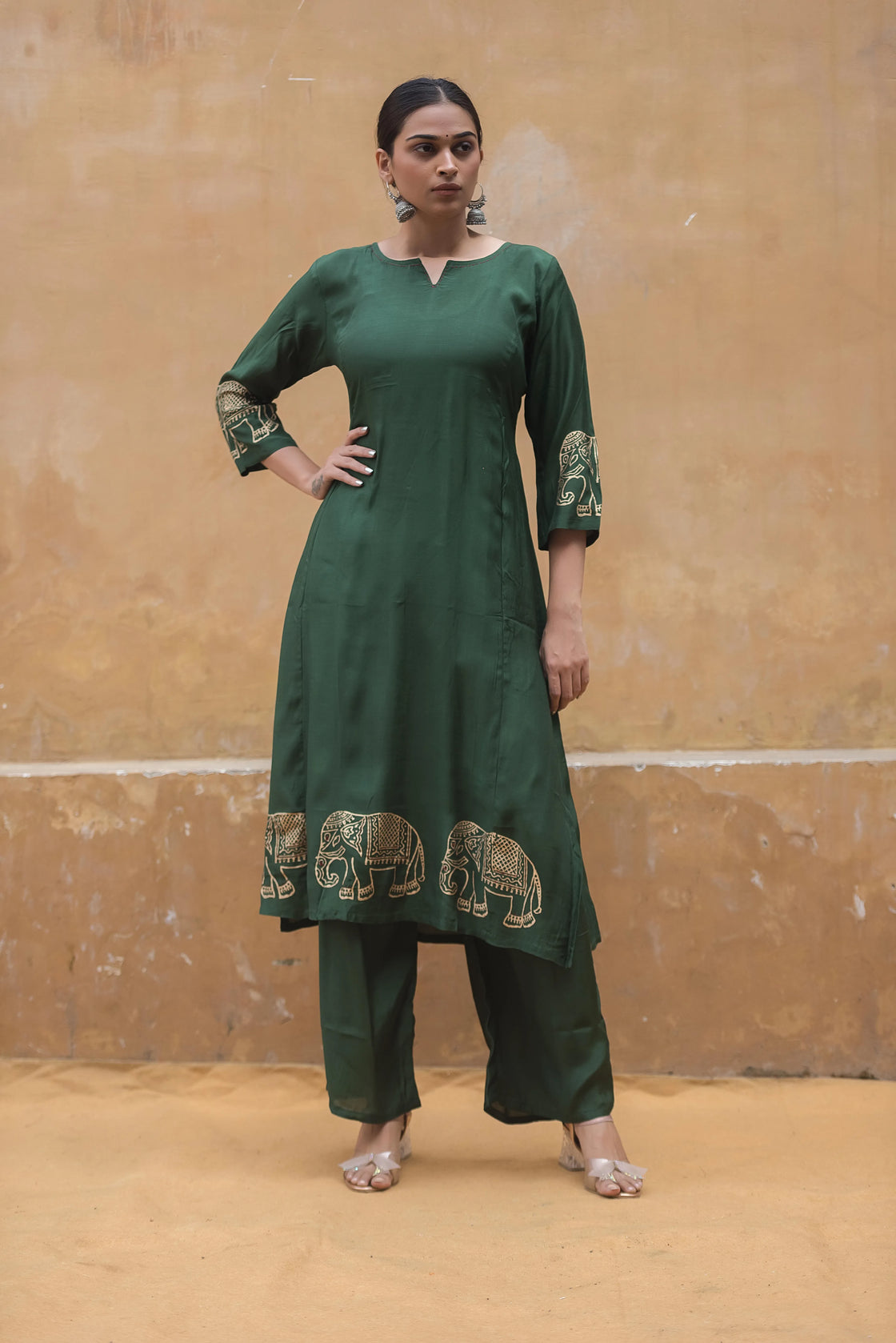 Woman posing in a bottle green muslin kurti pant set, hand on hip, showcasing confidence and elegance.