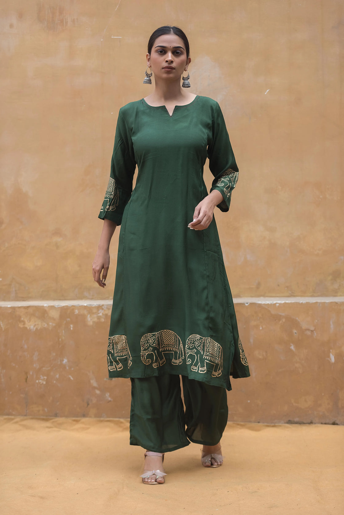 Woman walking pose in a bottle green muslin kurti pant set, showcasing its flowy silhouette.