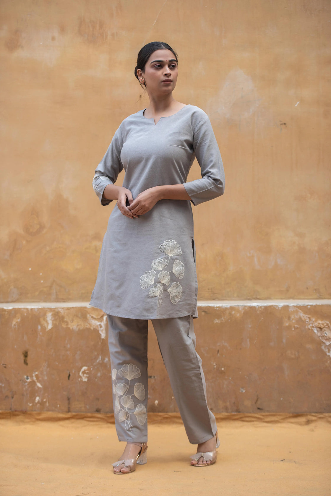 Woman wearing a grey flex cotton co-ord set with floral embroidery, standing in an airport setting.