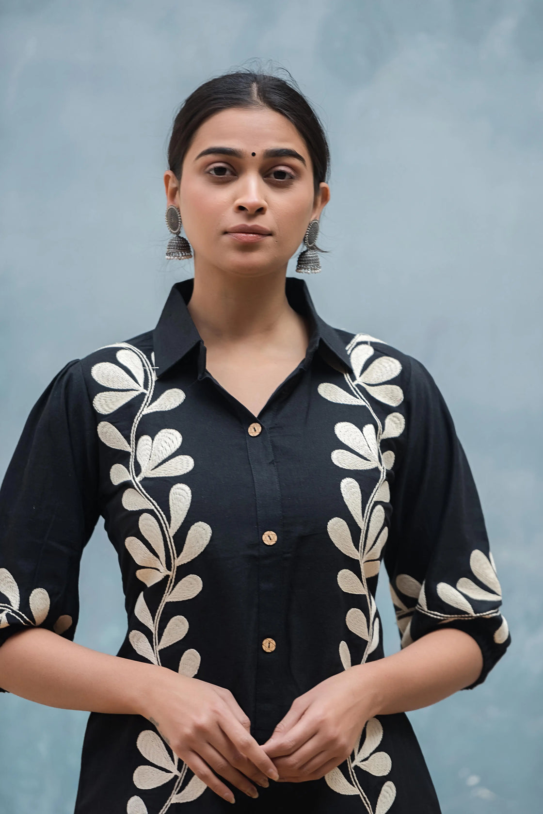 Woman wearing a black flex cotton co-ord set with embroidered white flowers, close-up short.