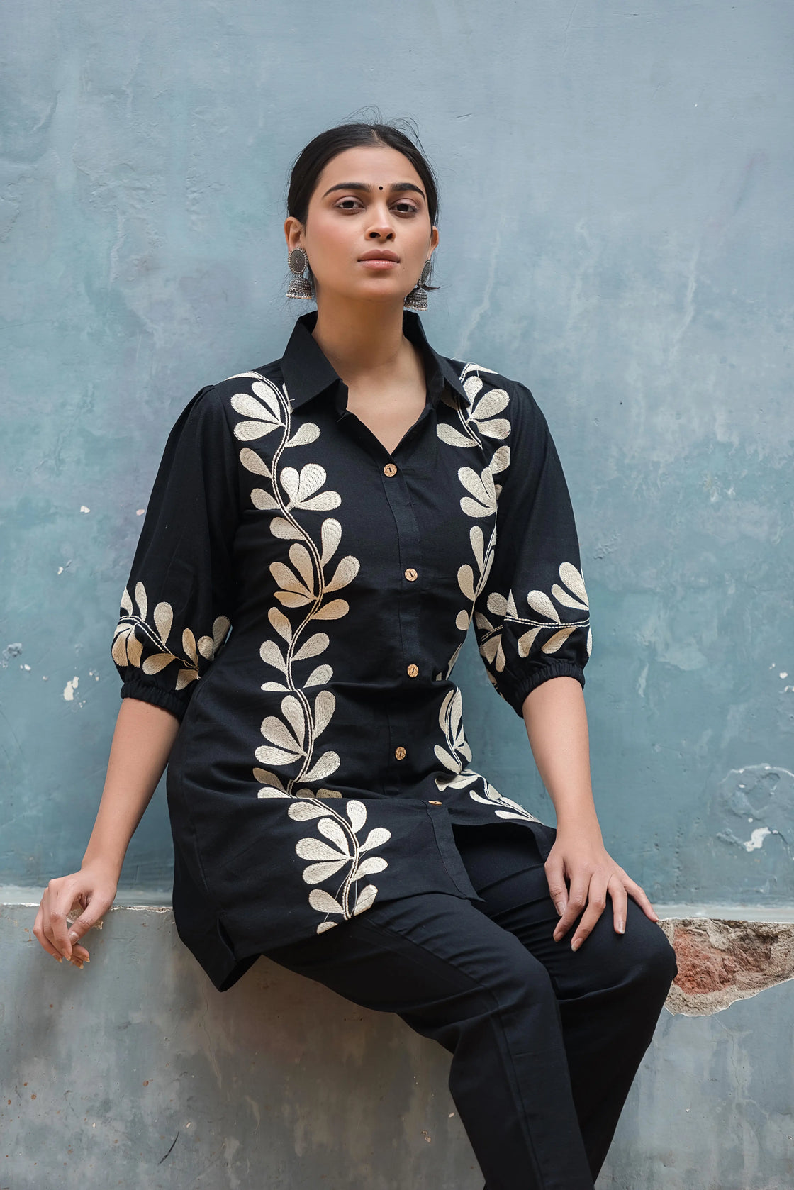 Woman wearing a black flex cotton co-ord set with embroidered white flowers.